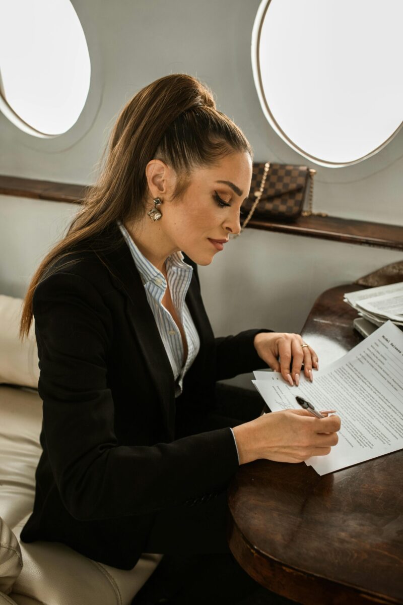 Confident businesswoman in formal attire signing documents on a private jet